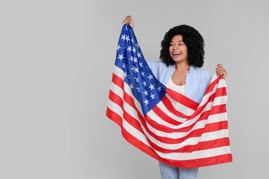 Photo of 4th of July - Independence Day of USA. Happy woman with American flag on light grey background, space for text