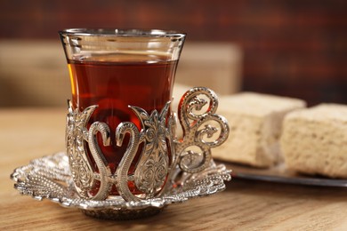 Photo of Glass of traditional Turkish tea in vintage holder on wooden table, closeup. Space for text