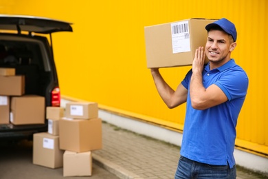 Photo of Courier with parcel near delivery van outdoors. Space for text