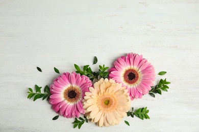 Photo of Flat lay composition with beautiful bright gerbera flowers on wooden background, top view. Space for text