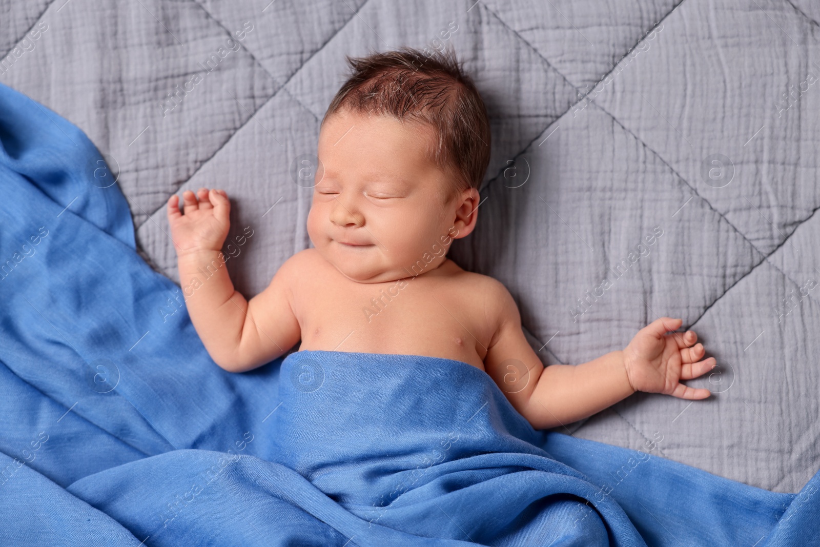Photo of Adorable newborn baby sleeping under blue blanket on bed, top view