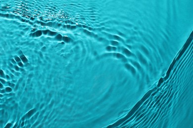 Rippled surface of clear water on light blue background, closeup