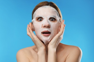 Photo of Emotional woman with cotton mask sheet on face against color background