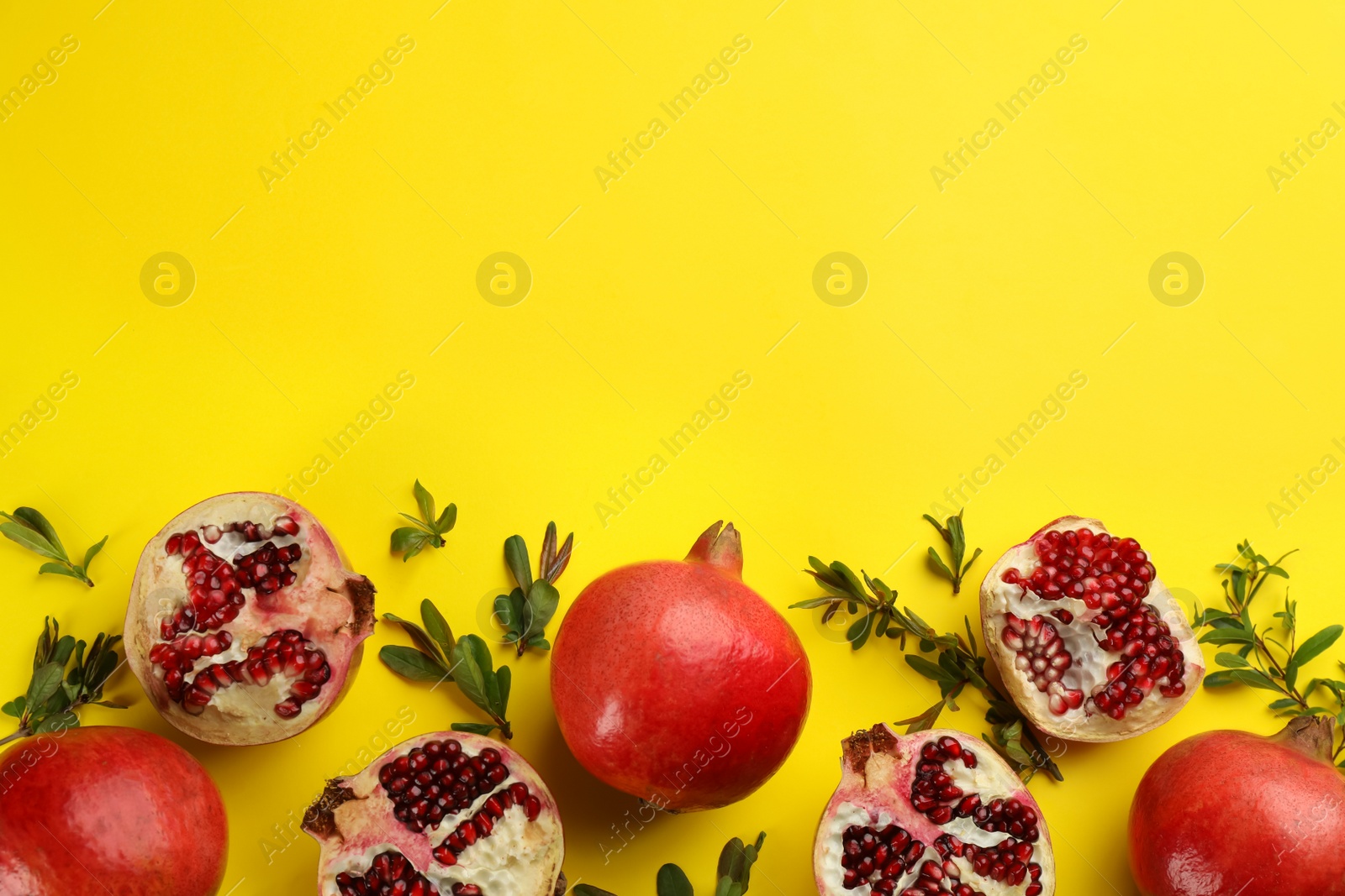 Photo of Flat lay composition with ripe pomegranates on yellow background. Space for text