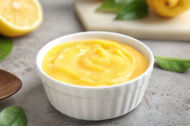 Delicious lemon curd in bowl on grey table, closeup