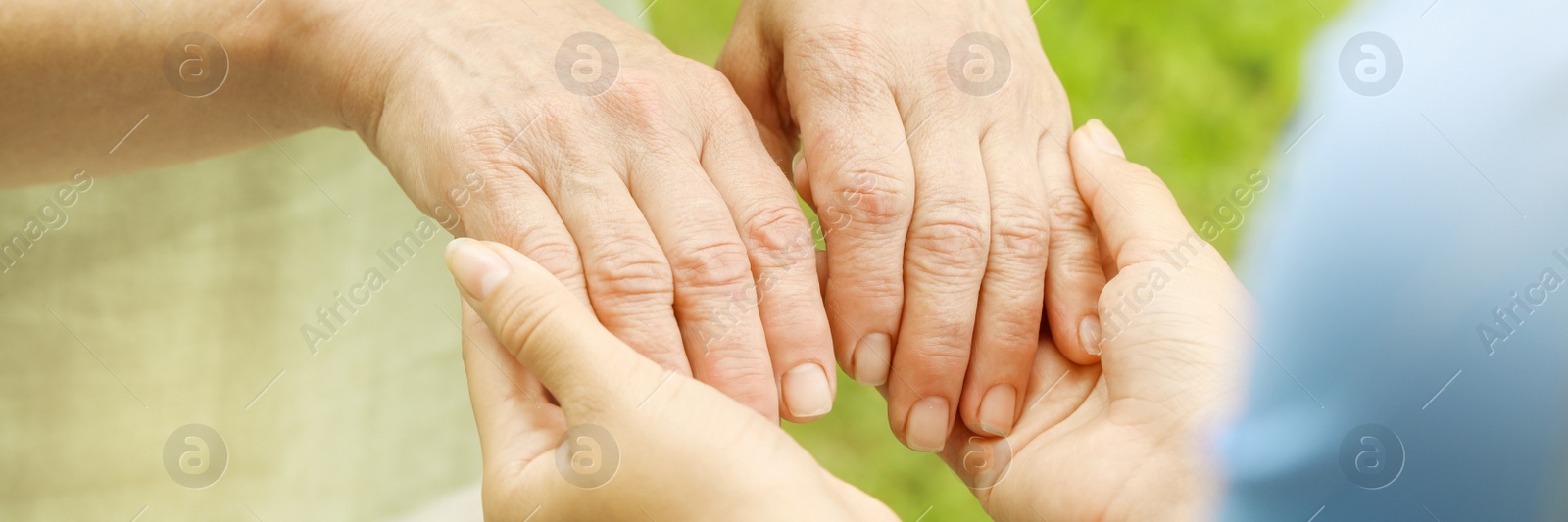 Image of Elderly woman and caregiver holding hands outdoors, closeup. Banner design