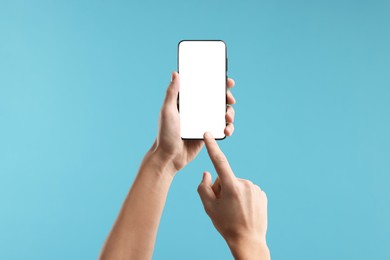 Photo of Man using smartphone with blank screen on light blue background, closeup. Mockup for design