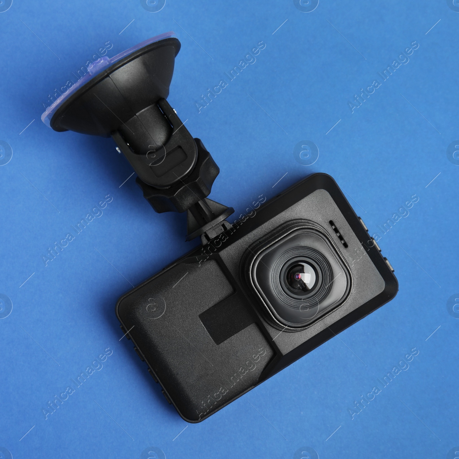 Photo of Modern car dashboard camera with suction mount on blue background, top view