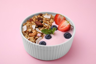 Photo of Tasty granola, yogurt and fresh berries in bowl on pink background, closeup. Healthy breakfast