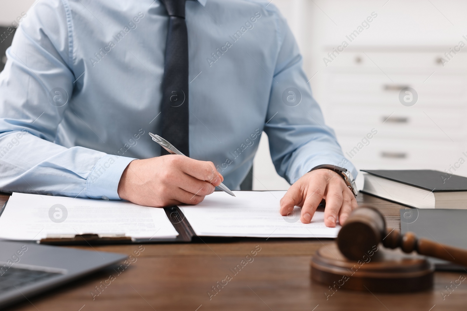 Photo of Lawyer working with documents at wooden table in office, closeup