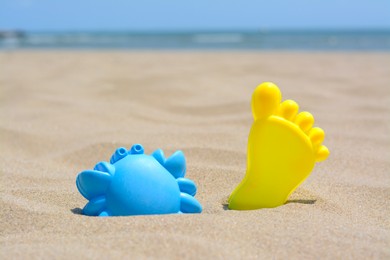 Photo of Colorful plastic molds on sand near sea, space for text. Beach toys