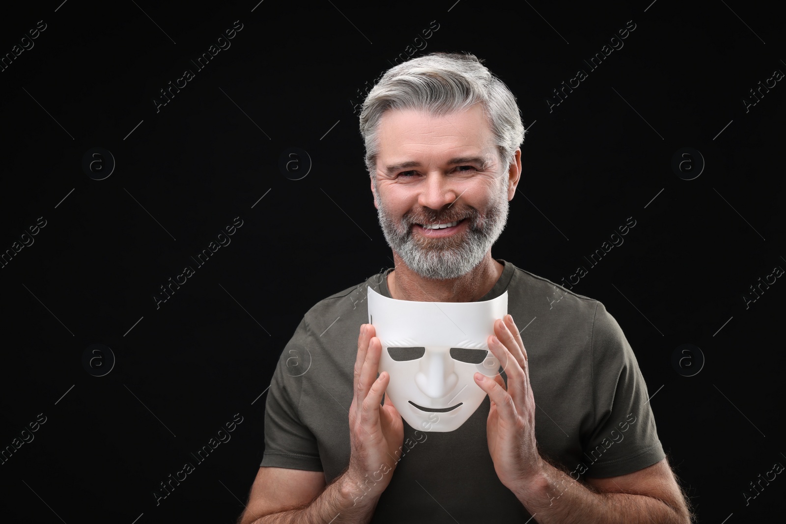 Photo of Multiple personality concept. Happy man with mask on black background