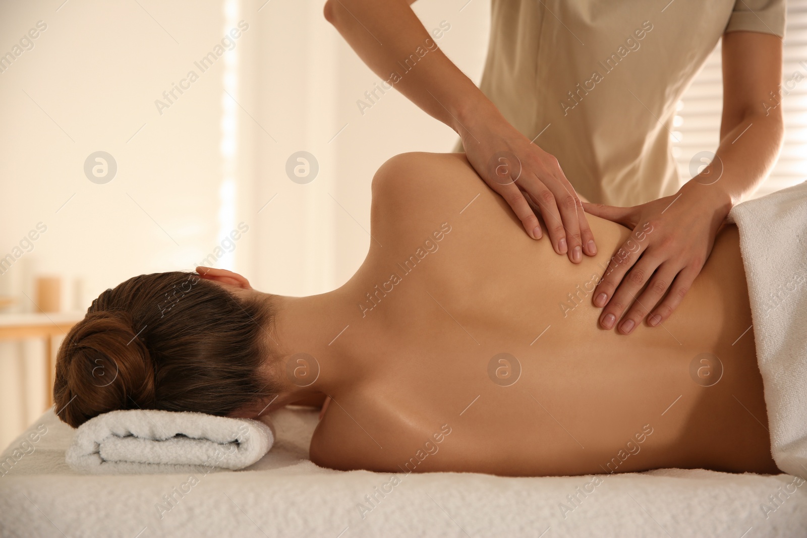 Photo of Young woman receiving back massage in spa salon