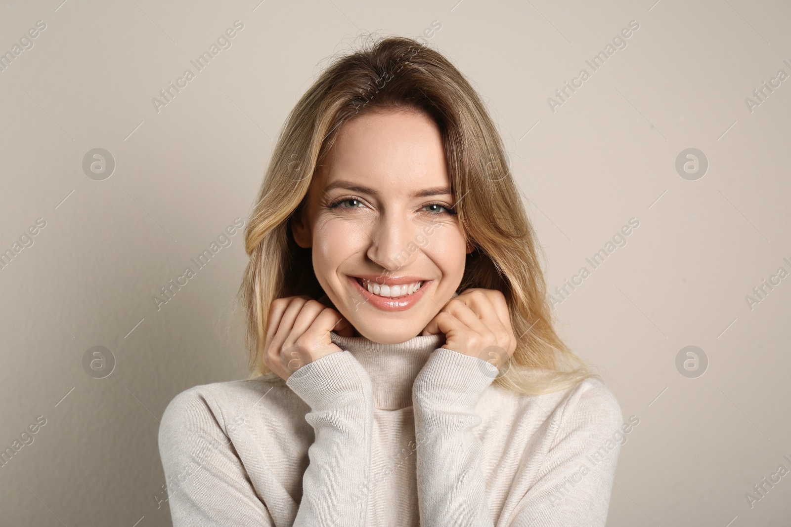 Photo of Portrait of happy young woman with beautiful blonde hair and charming smile on beige background