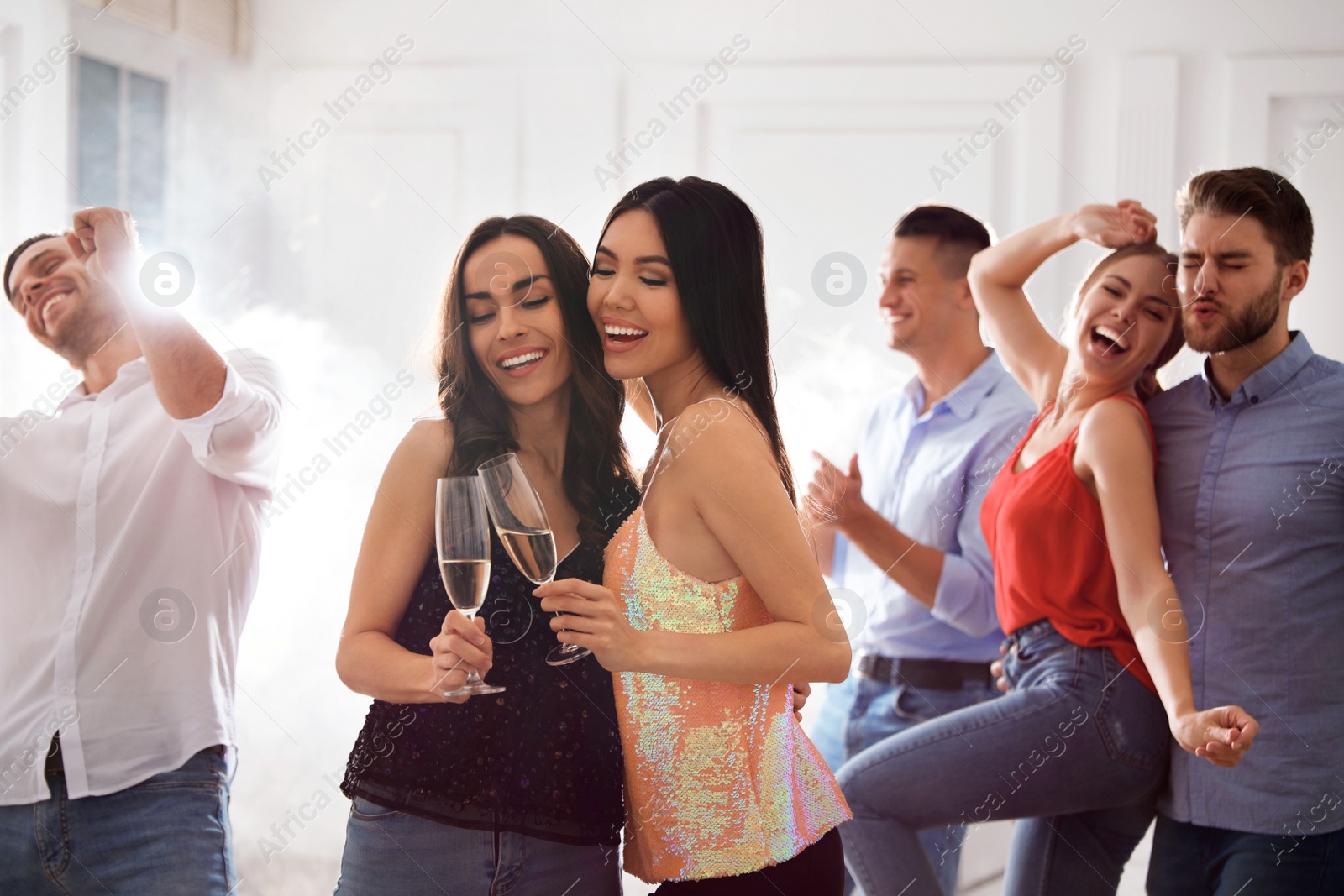 Photo of Couple of happy friends with champagne dancing at party