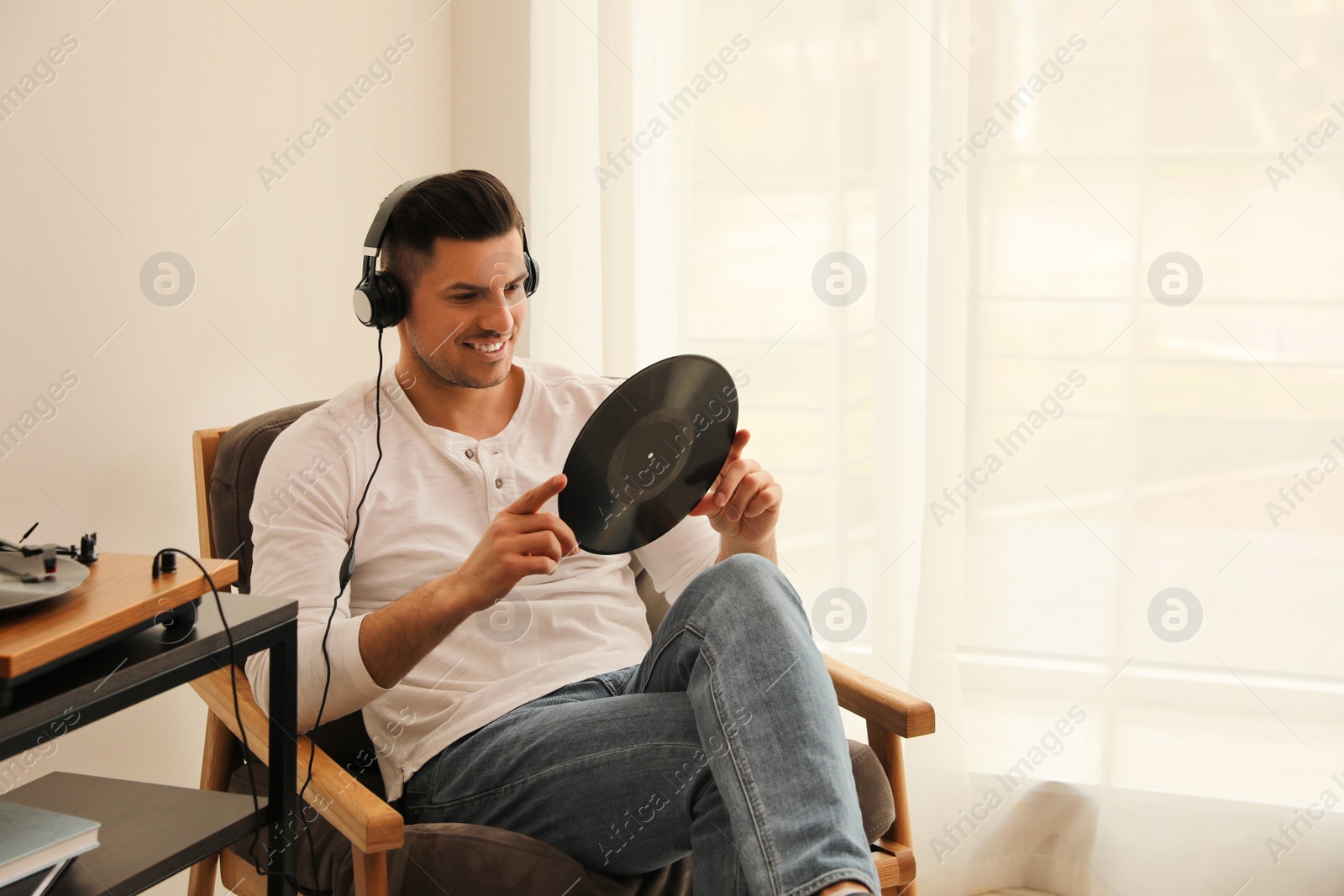 Photo of Happy man listening to music with turntable at home