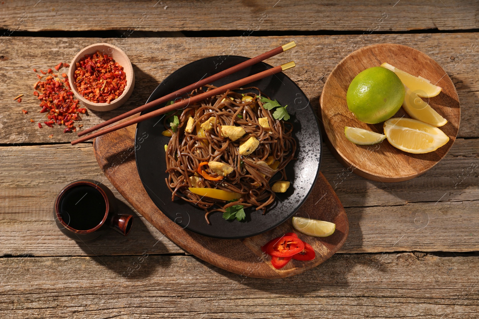 Photo of Stir-fry. Tasty noodles with vegetables and meat served on wooden table, flat lay