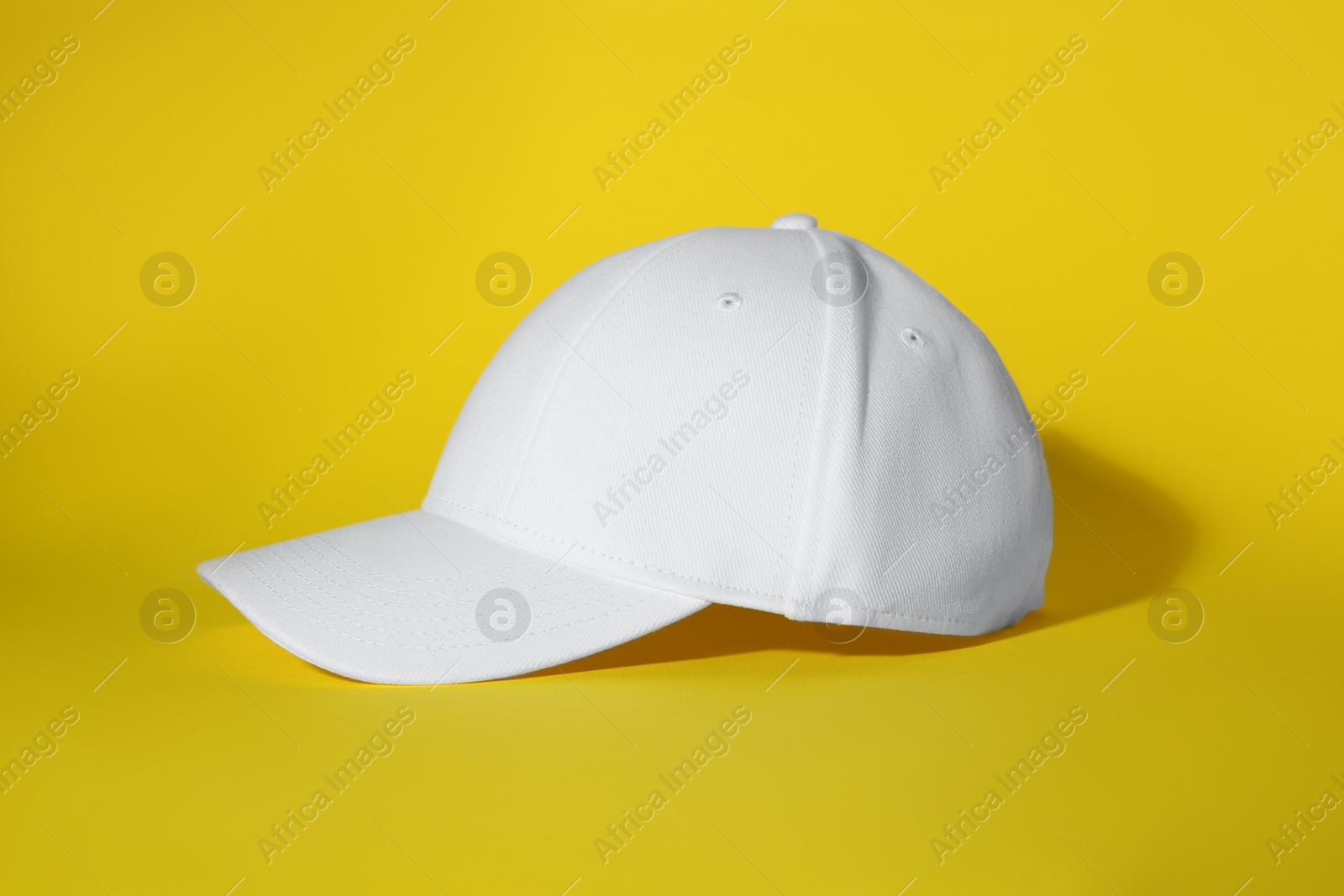 Photo of Stylish white baseball cap on yellow background