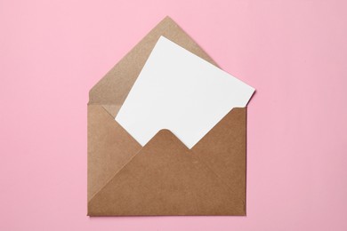 Photo of Letter envelope with card on pink background, top view