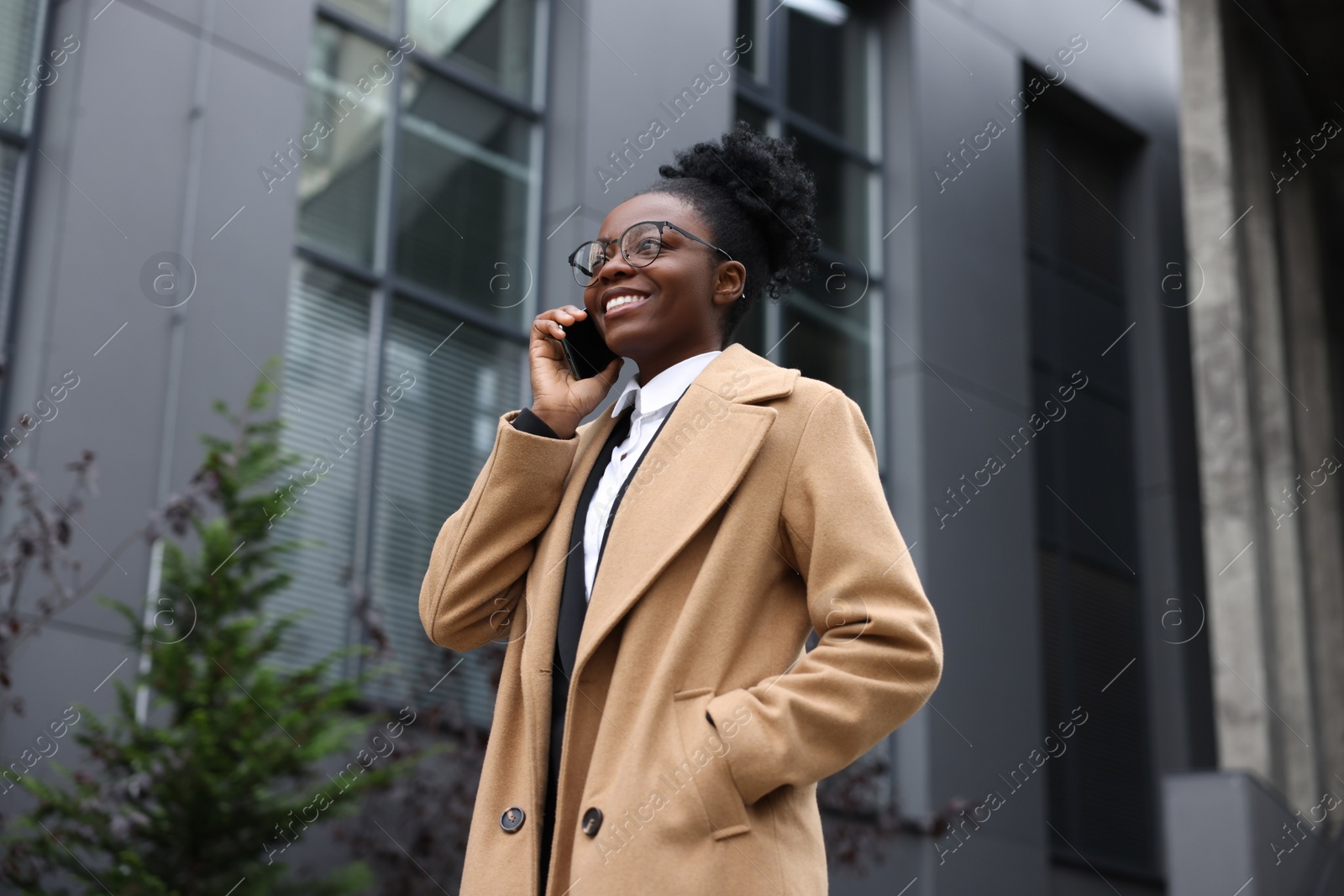 Photo of Happy woman talking on smartphone outdoors. Lawyer, businesswoman, accountant or manager