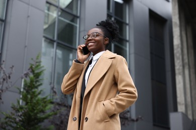 Photo of Happy woman talking on smartphone outdoors. Lawyer, businesswoman, accountant or manager