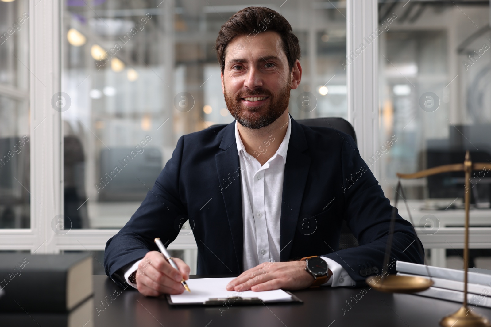 Photo of Portrait of smiling lawyer at table in office