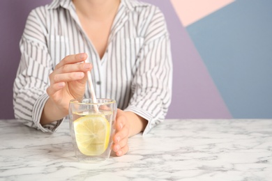 Young woman drinking water with lemon at table