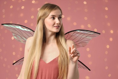 Photo of Beautiful girl in fairy costume with wings on pink background