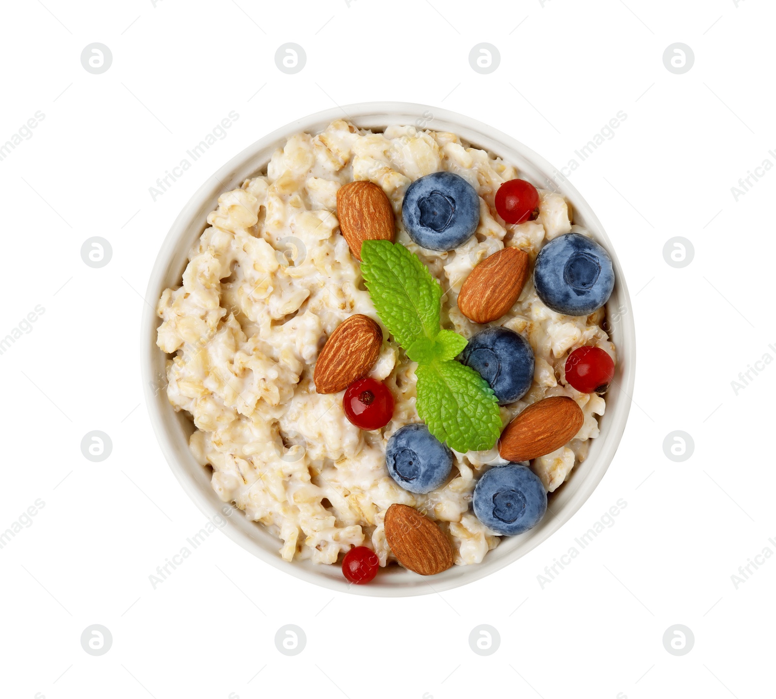 Photo of Ceramic bowl with oatmeal, berries. almonds and mint isolated on white, top view