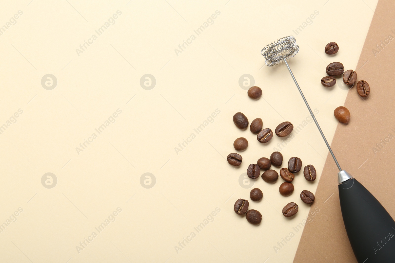 Photo of Milk frother wand and coffee beans on color background, top view. Space for text