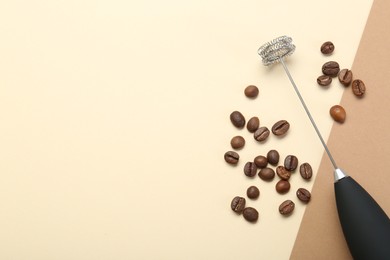 Milk frother wand and coffee beans on color background, top view. Space for text