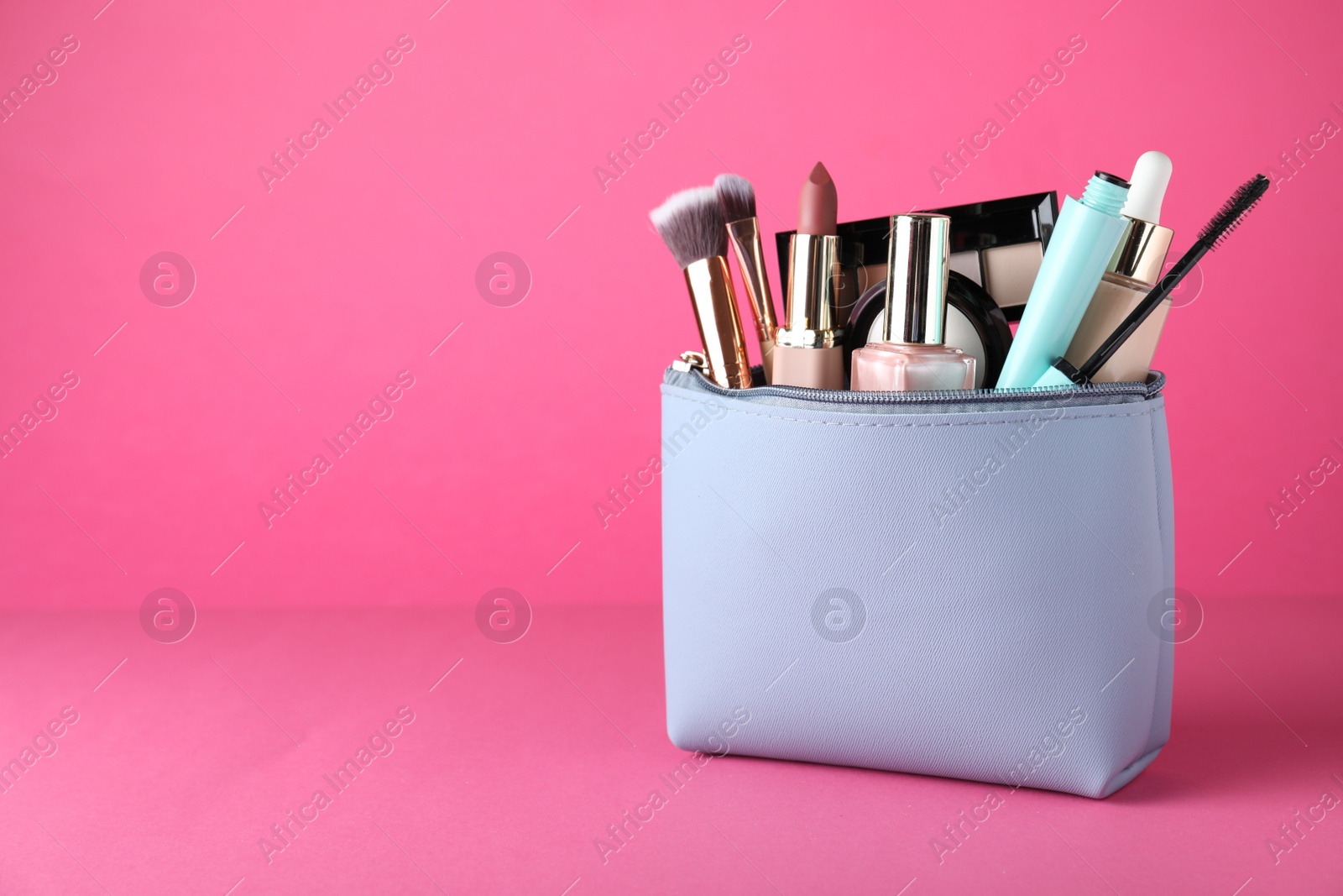 Photo of Cosmetic bag with makeup products and accessories on pink background. Space for text