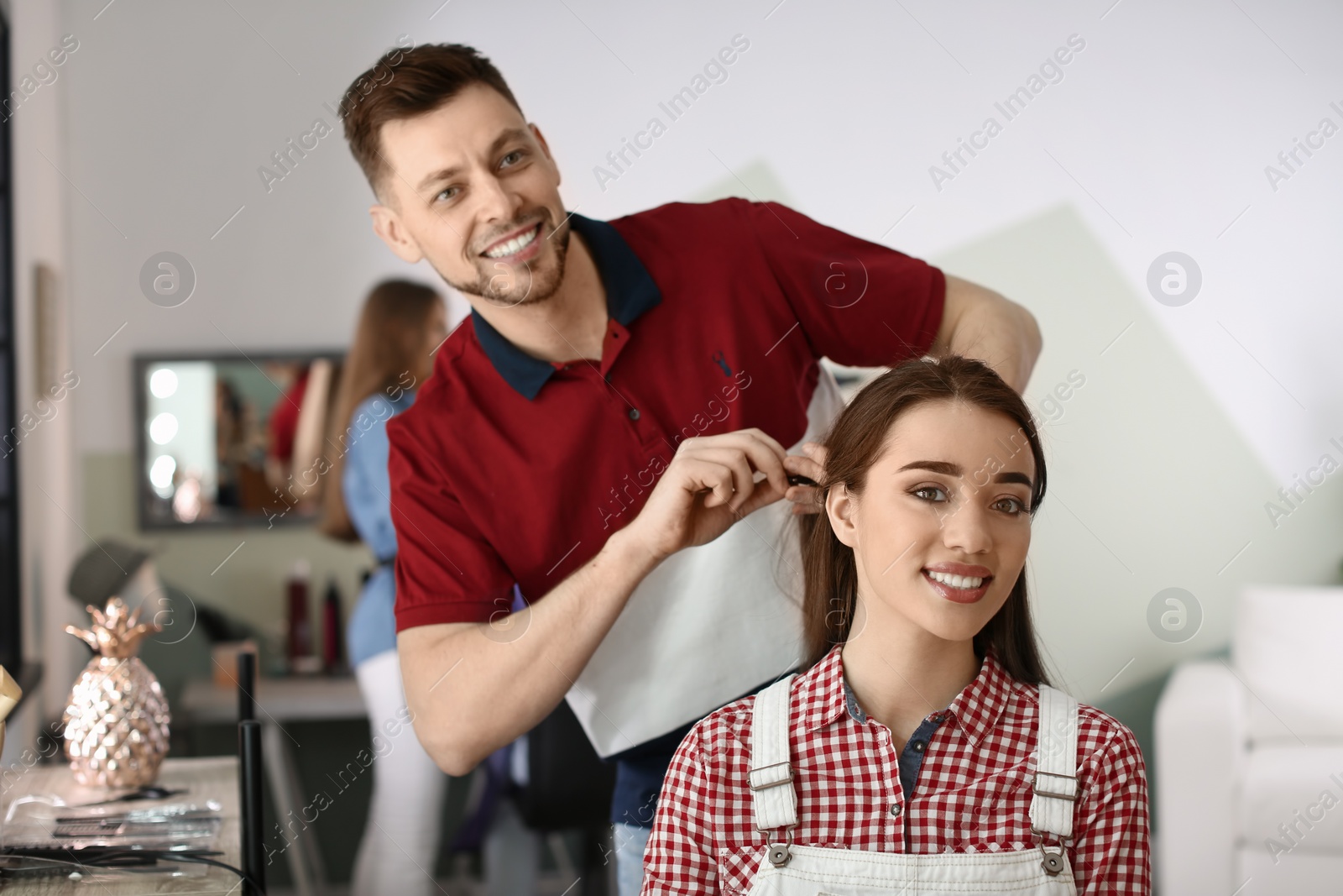 Photo of Professional hairdresser working with client in beauty salon