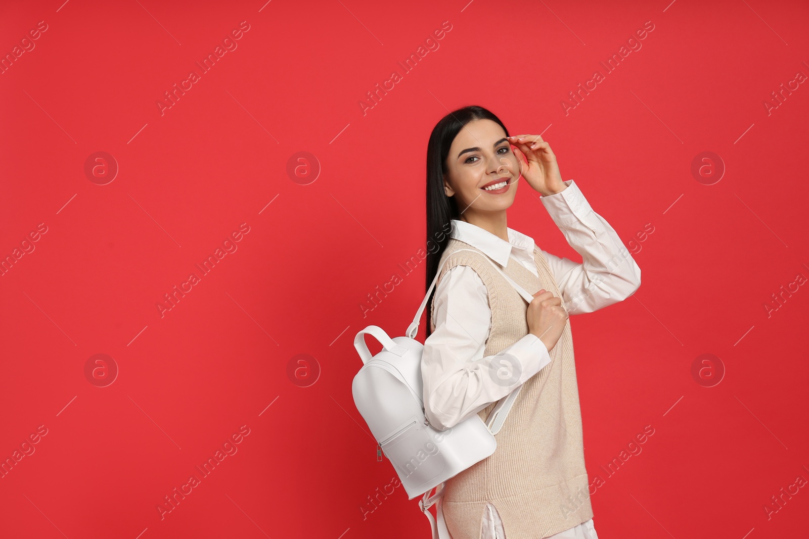 Photo of Young woman with stylish backpack on red background. Space for text