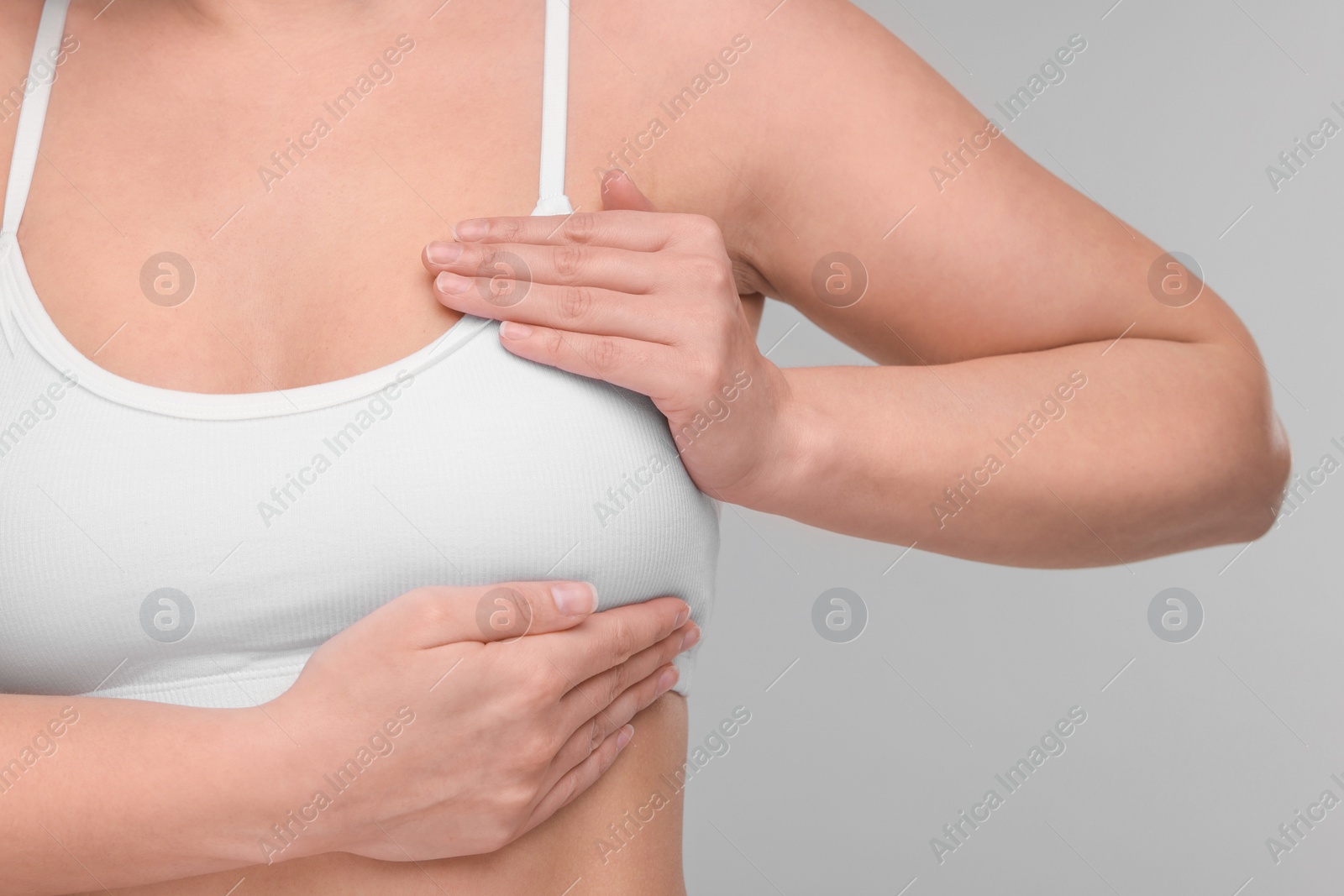 Photo of Mammology. Woman doing breast self-examination on light grey background, closeup