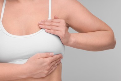 Mammology. Woman doing breast self-examination on light grey background, closeup