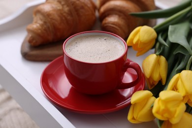 Photo of Morning coffee, flowers and croissants on white wooden tray, closeup