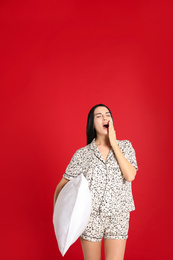 Young woman with pillow on red background