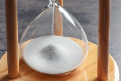 Photo of Hourglass with flowing sand on table, closeup. Time management