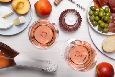 Photo of Delicious rose wine and snacks on white wooden table, flat lay