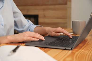 Photo of Woman working with modern laptop at wooden table, closeup
