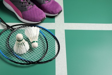 Photo of Feather badminton shuttlecocks, rackets and sneakers on court, space for text