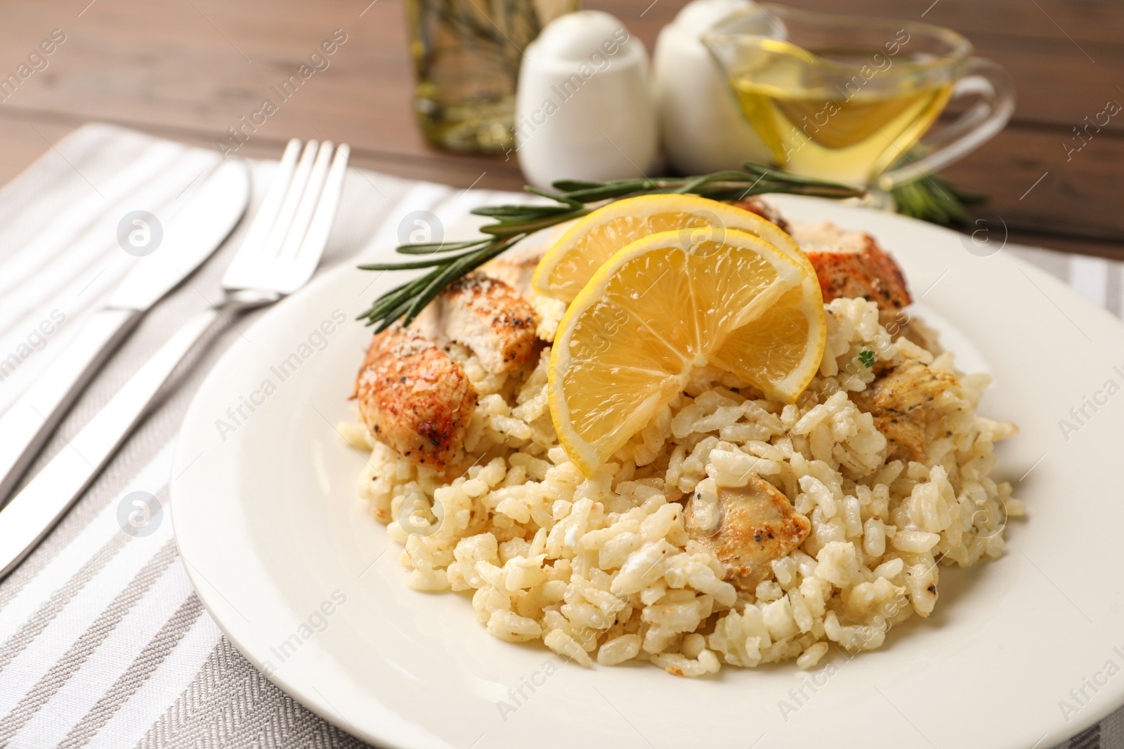 Photo of Delicious chicken risotto with lemon slices on table