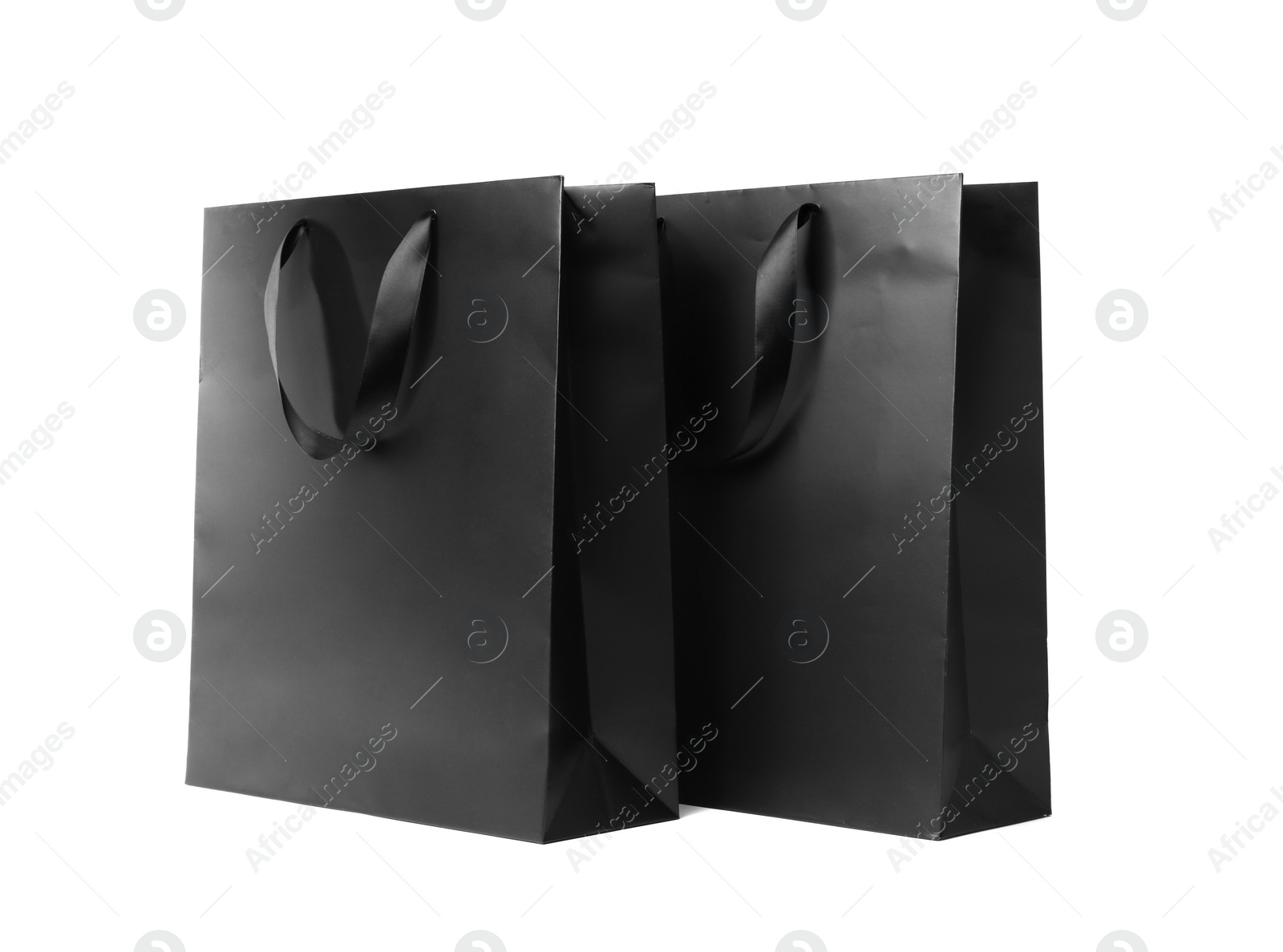 Photo of Paper shopping bags with ribbon handles on white background. Mockup for design