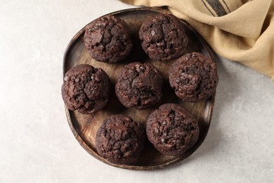 Photo of Board with delicious chocolate muffins on light table, top view