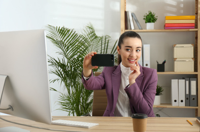 Lazy employee taking selfie at table in office