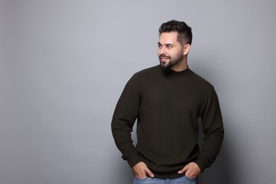 Happy man in stylish sweater on grey background, space for text
