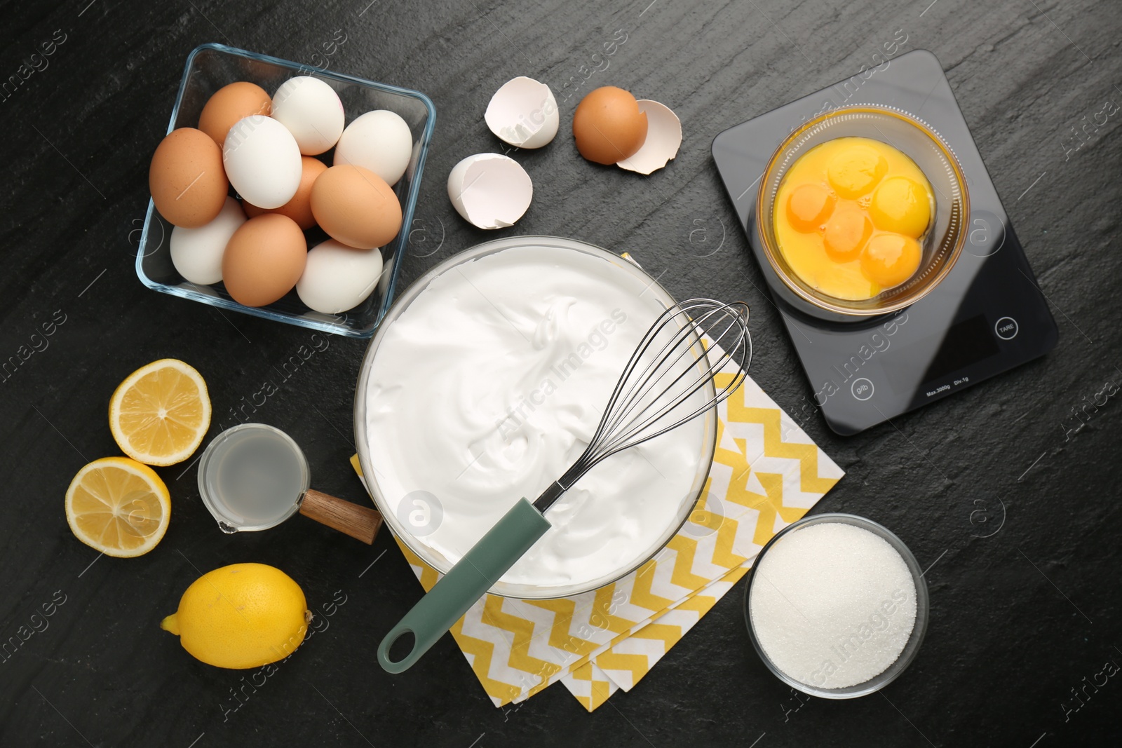 Photo of Bowl with whipped cream, whisk and ingredients on black table, flat lay