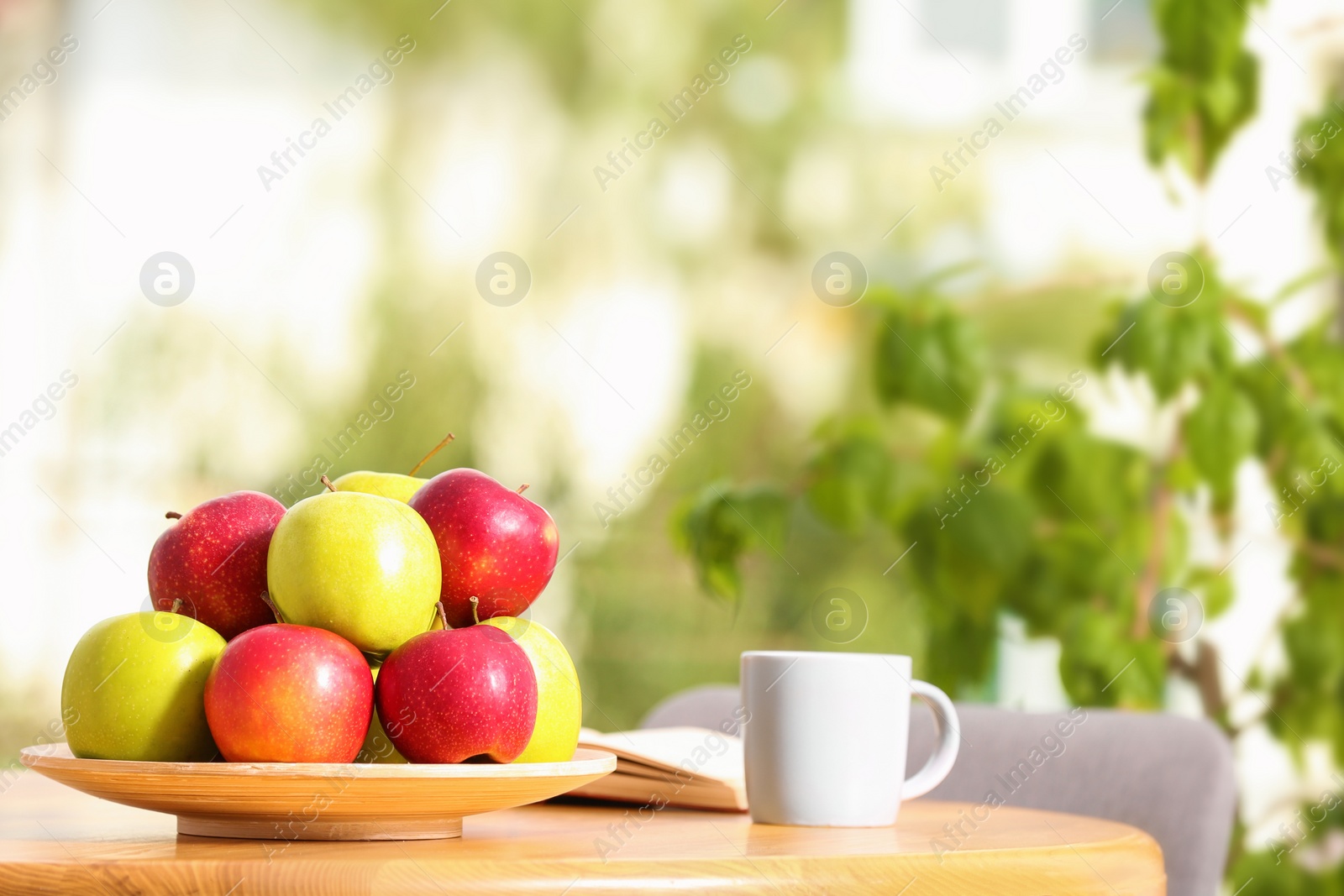 Photo of Plate with different sweet apples and cup of coffee on table in room