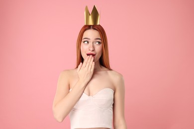 Photo of Emotional young woman with princess crown on pink background